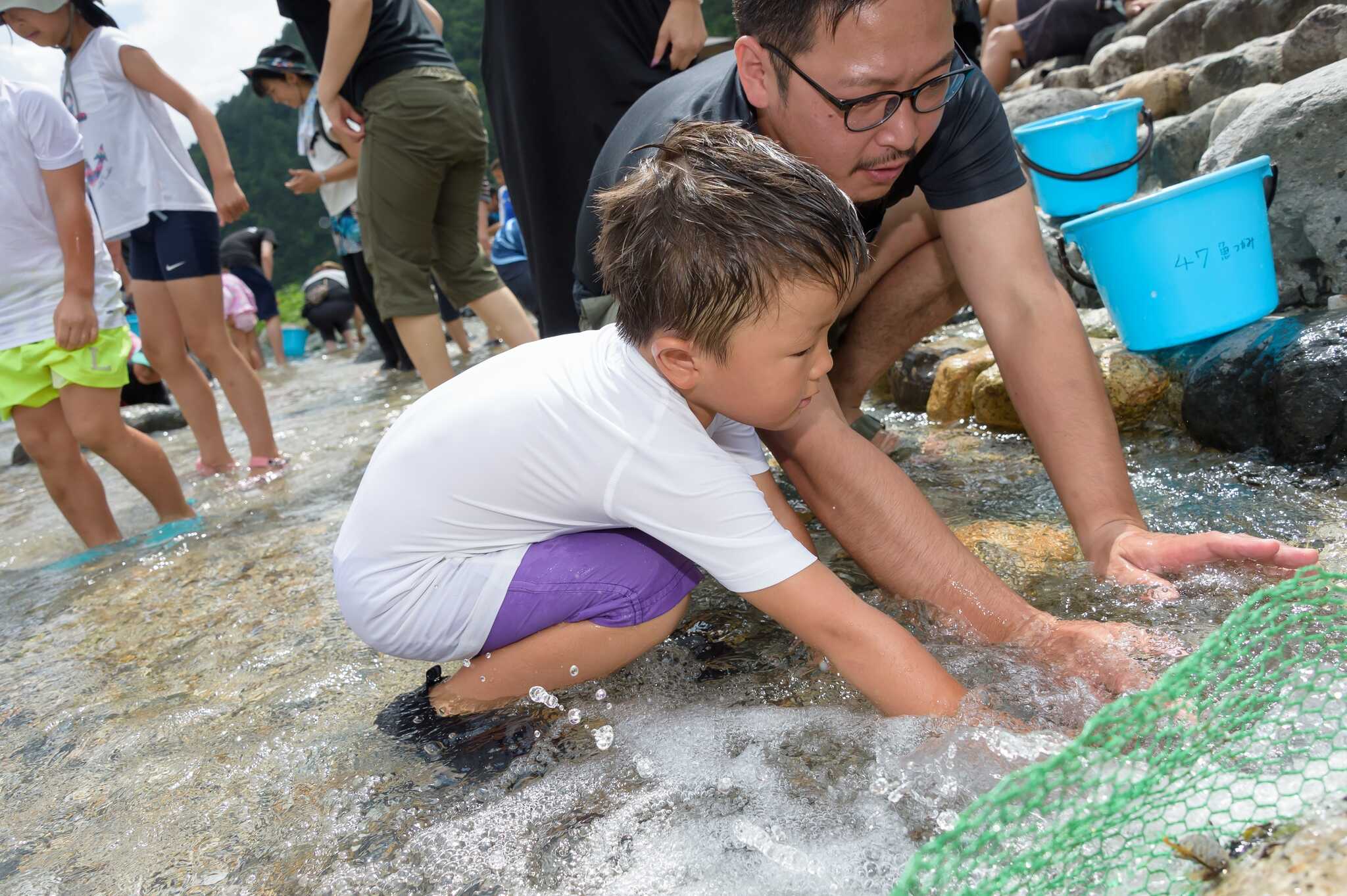 冷たく澄んだ川での魚のつかみどり。獲った魚を自分で捌いて、焼いて食べることができます。